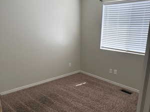 Unfurnished room featuring carpet floors, visible vents, and baseboards