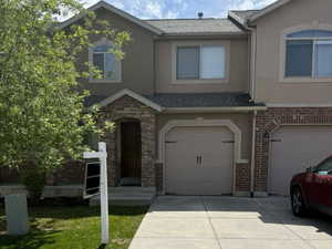 View of property featuring a garage, stucco siding, and concrete driveway