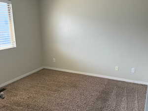 Carpeted empty room featuring baseboards