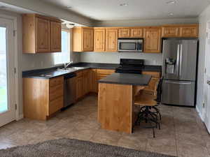 Kitchen featuring appliances with stainless steel finishes, healthy amount of natural light, dark countertops, a breakfast bar area, and a textured ceiling