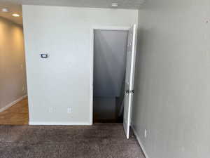 Carpeted empty room featuring baseboards and a textured ceiling