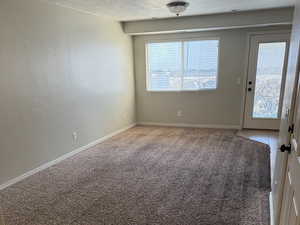 Carpeted empty room with a wealth of natural light, baseboards, and a textured ceiling