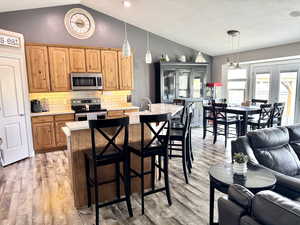 Kitchen featuring lofted ceiling, stainless steel appliances, light countertops, french doors, and open floor plan