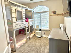 Carpeted bedroom with baseboards and multiple windows