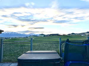 View of yard with a rural view, a hot tub, fence, and a mountain view