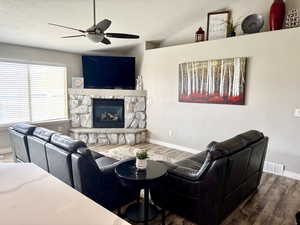 Living room featuring a textured ceiling, wood finished floors, visible vents, and ceiling fan