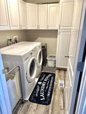 Laundry room with cabinet space, wood finished floors, visible vents, and washing machine and clothes dryer