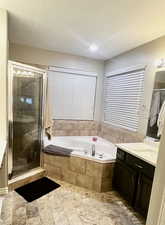 Bathroom with a bath, vanity, and a stall shower