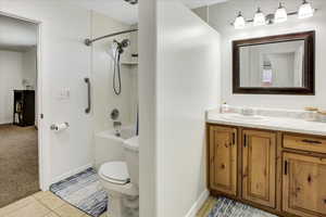 Bathroom with tile patterned flooring, toilet, vanity, tub / shower combination, and baseboards