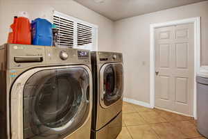 Washroom featuring washing machine and clothes dryer, baseboards, laundry area, and light tile patterned flooring