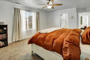 Carpeted bedroom featuring visible vents, a ceiling fan, baseboards, and connected bathroom