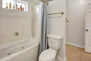 Full bathroom featuring baseboards, a combined bath / shower with jetted tub, tile patterned flooring, and toilet
