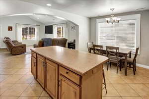 Kitchen featuring a center island, open floor plan, light tile patterned flooring, arched walkways, and visible vents