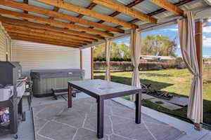 View of patio with fence and a hot tub