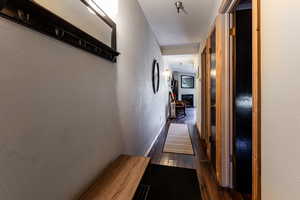 Hallway with a textured wall, baseboards, and dark wood-style flooring