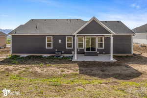 Back of property featuring central air condition unit, roof with shingles, and a patio