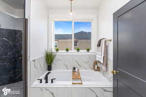 Full bath featuring a garden tub and a marble finish shower