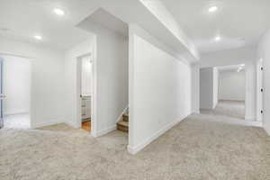 Hallway with baseboards, carpet flooring, recessed lighting, and stairway