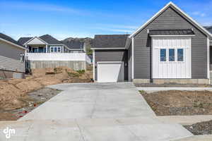 Ranch-style home featuring board and batten siding, driveway, a garage, and fence