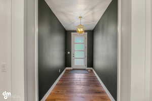 Entryway featuring wood finished floors, baseboards, and a notable chandelier