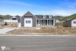 View of front facade with driveway, a mountain view, a porch, roof with shingles, and a standing seam roof