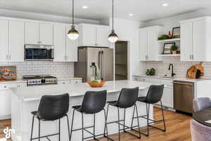 Kitchen featuring a kitchen breakfast bar, a sink, tasteful backsplash, open shelves, and appliances with stainless steel finishes