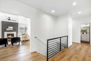 Hall featuring baseboards, an upstairs landing, light wood finished floors, and recessed lighting