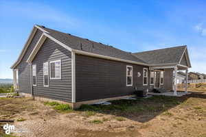 View of home's exterior featuring cooling unit, roof with shingles, and a patio