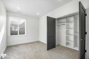 Unfurnished bedroom with a closet, light colored carpet, baseboards, visible vents, and recessed lighting