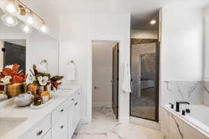 Full bath featuring double vanity, a shower stall, marble finish floor, and a bath