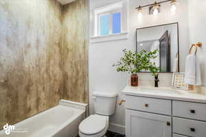 Bathroom with toilet, vanity, and baseboards