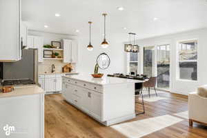 Kitchen with open shelves, a sink, a kitchen bar, white cabinets, and freestanding refrigerator