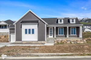 View of front of home with a porch, an attached garage, a shingled roof, and board and batten siding