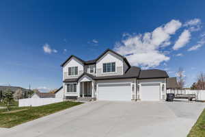 Traditional home featuring driveway, fence, an attached garage, board and batten siding, and a front yard