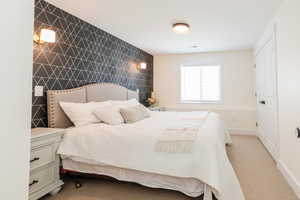 Carpeted bedroom featuring baseboards, visible vents, and tile walls