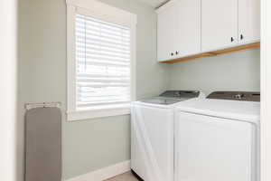 Laundry area featuring baseboards, cabinet space, and washer and clothes dryer