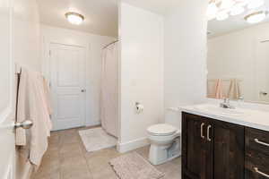 Bathroom with baseboards, tile patterned flooring, vanity, and toilet