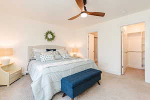 Bedroom with a spacious closet, baseboards, a ceiling fan, and carpet flooring