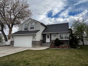 Tri-level home featuring concrete driveway, stucco siding, an attached garage, and a front lawn