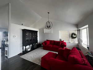 Living area with a chandelier, wood finished floors, and lofted ceiling