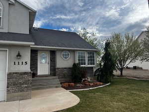 View of front of property featuring a garage, a front yard, stucco siding, and a shingled roof