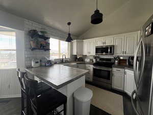 Kitchen featuring a sink, appliances with stainless steel finishes, a peninsula, and white cabinetry
