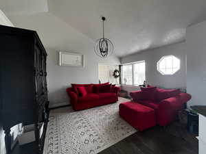 Living area with a notable chandelier, baseboards, wood finished floors, and lofted ceiling