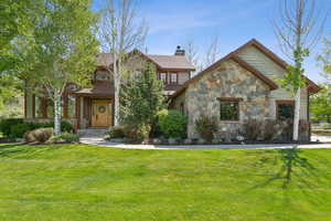 View of front facade featuring stone siding, a front lawn, and a chimney
