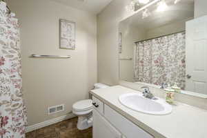 Bathroom with baseboards, visible vents, toilet, and vanity