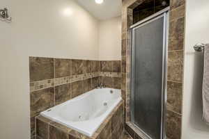 Full bath with a jetted tub and a stall shower