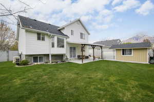 Rear view of property with fence, a yard, a patio, a mountain view, and a garage