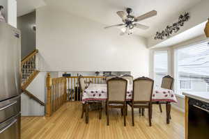 Dining room with vaulted ceiling, a ceiling fan, and light wood-style floors