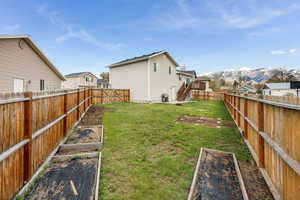 View of yard featuring stairs, a deck with mountain view, a vegetable garden, and a fenced backyard