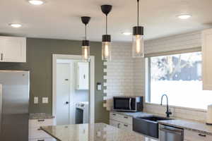 Kitchen with white cabinetry, recessed lighting, a sink, stainless steel appliances, and decorative backsplash